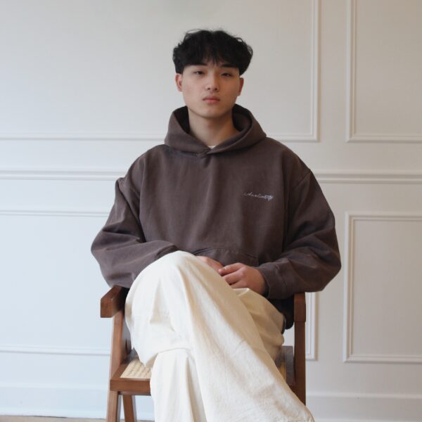 Model wearing clove brown hoodie in natural light studio setting