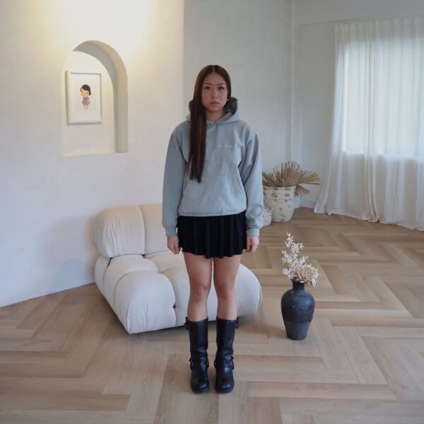 Female model wearing sage hoodie in a bright modern room